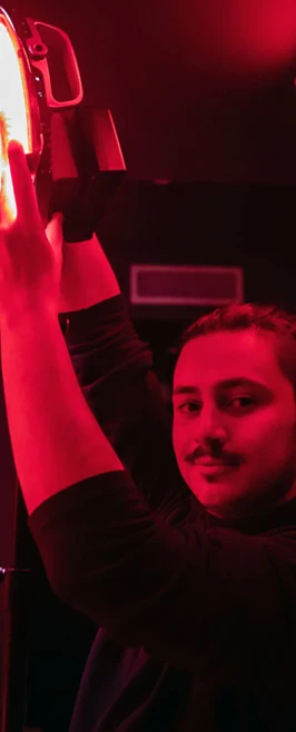 Student adjusting a red safelight in a darkroom during a photography session. Student adjusting a red safelight in a darkroom during a photography session.